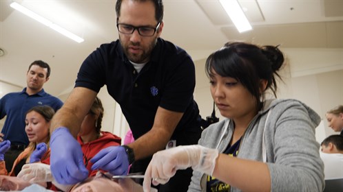 Advanced care paramedic Vincent Dazé teaches a high school student suturing at the Fort Chipewyan skills day event.