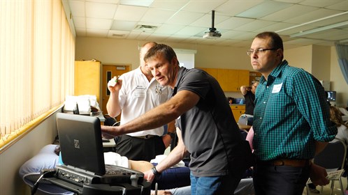 Dr. Stefan Badenhorst (C) points to screen while instructor Dr. Andries Esterhuizen (L) and Dr. Dr. Thian Müller (R) look on.